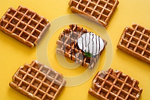 Waffles with chocolate sauce, ice cream and mint on yellow background