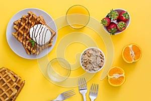 Waffles with chocolate sauce, ice cream and mint on yellow background