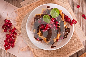 Waffles with chocolate topping and red currant.