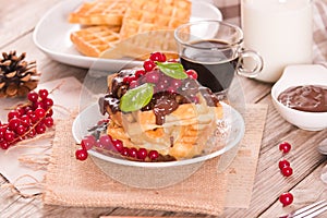 Waffles with chocolate topping and red currant.