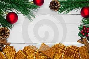 Waffles with cinnamon and anise and branch christmas tree and red ball with cone on white wooden vintage background