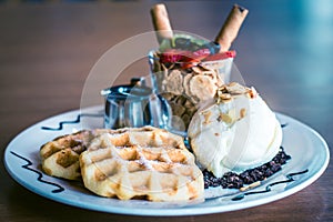 Waffles dusted with icing sugar and iceream and fruit on the side