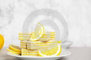 Waffles with lemon and milk filling. Lemon slices lying on saucer on blurred background. Yummy and sweet dessert. Bun-fight. Copy