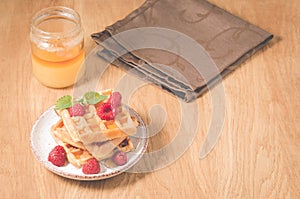 Waffles With raspberry in plate. Breakfast/Homemade waffles with raspberry in plate, honey on a wooden table, selective focus