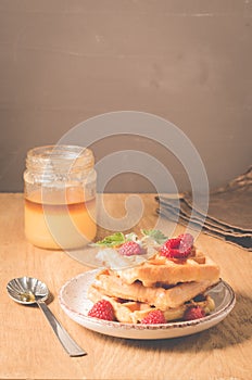 Waffles With raspberry in plate. Sweet dessert menu. Breakfast/Homemade waffles with raspberry, honey in plate on a old wooden