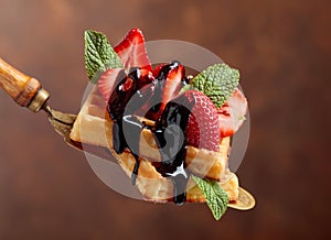 Waffles with strawberries, mint and chocolate sauce