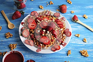 Waffles with strawberry on white plate on blue background.