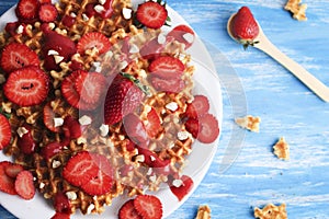 Waffles with strawberry on white plate on blue background. Top view flat lay