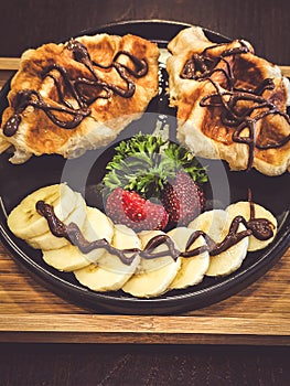 Waffles topped with chocolate and fresh strawberries