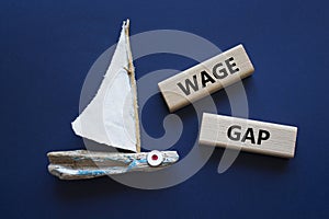Wage Gap symbol. Concept words Wage Gap on wooden blocks. Beautiful deep blue background with boat. Business and Wage Gap concept