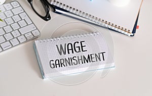 Wage Garnishment T, text on white paper on black envelope near financial charts