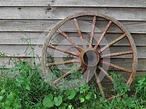 Wagon wheel against old board wall.