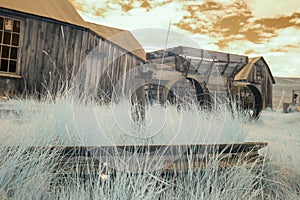 Wagon wheel and wagon in field, in Bodie, California in infrared