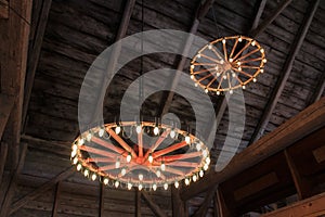 Wagon wheels hung from the ceiling of a barn with lights for a traditional old-fashioned wedding celebration