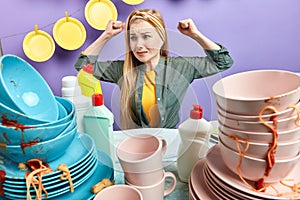 Waht dirty plates.upset caucasian woman looks with dissatisfcation at messy table