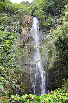 Wailua Falls cascading down a rocky, volcanic cliffside in a rainforest in Hana, Maui photo
