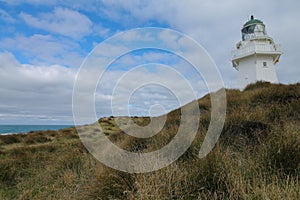 Waipapa Point Lighthouse with dunes and cloudy sky