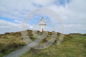 Waipapa Point Lighthouse with dunes and cloudy sky