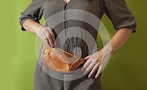 Waist bag made from natural leather close-up view on the unrecognizable woman on the green background