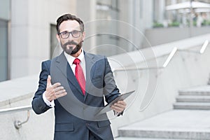 Waist up of affluent businessman having a talk with you while holding a tablet in hand photo