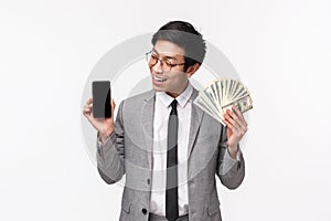 Waist-up of lucky, successful young male IT businessman in grey suit, getting rich using application, showing something