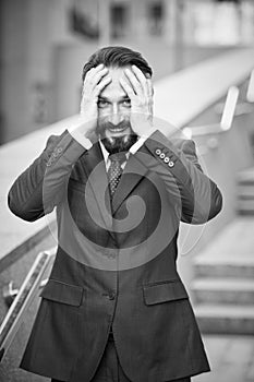 Waist up photo of excited businessman covering his head with hands outdoors