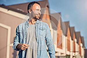 Accomplished man posing near his new apartment