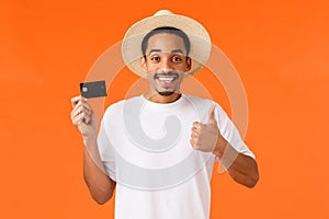 Waist-up portrait attractive smiling african american male tourist using bank service abroad, showing thumb-up and