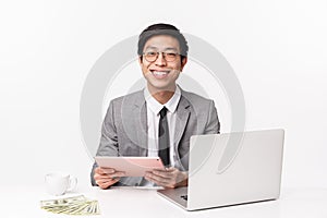 Waist-up portrait of cheerful, happy smiling asian office worker in suit, sitting at table studying chart using digital