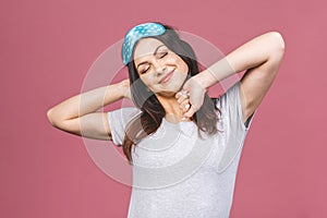 Waist up portrait of cheerful smiling girl in sleeping mask. Attractive funny female in stylish pajama standing and looking away.