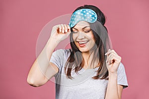 Waist up portrait of cheerful smiling girl in sleeping mask. Attractive funny female in stylish pajama standing and looking away.