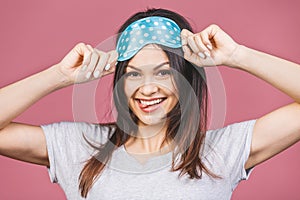 Waist up portrait of cheerful smiling girl in sleeping mask. Attractive funny female in stylish pajama standing and looking away.