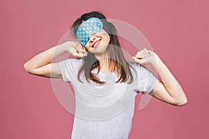 Waist up portrait of cheerful smiling girl in sleeping mask. Attractive funny female in stylish pajama standing and looking away.