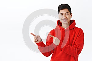 Waist-up portrait of handsome asian man in red hoodie give advice where find good company to get job, employement or