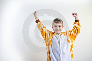 Waist up portrait of the happy little boy wearing giraffe pijamas, standing isolated over white background with raised