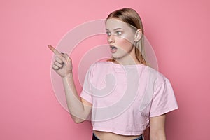 Waist up portrait of shocked and scared girl in stupor loking concerned and terrified pointing finger at upper left