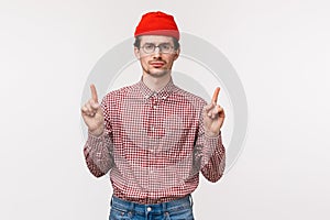 Waist-up portrait skeptical and unamused bored young man with beard, wear glasses and red beanie, look reluctant camera