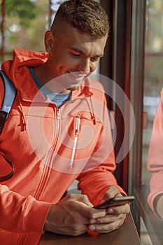 Pleased sportsman looking at his smartphone indoors