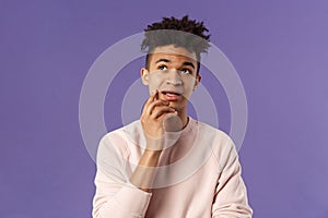 Waist-up portrait of thoughtful unsure young hispanic male student trying solve exercise, looking up thinking, pondering