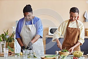 Two African American women cooking together in kitchen and doing food prep