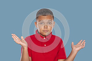 Waist up portrait  of a young boy  spreading his arms to the side regretting something against  blue  background