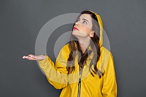Waist up of pretty Caucasian girl dressed in yellow raincoat in studio
