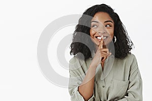 Waist-up shot of amused excited good-looking artistic african american woman with curly hairstyle smiling joyfully