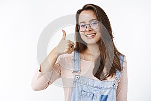 Waist-up shot of charming happy and delighted female freelancer assuring work done in time showing thumbs up and smiling