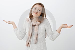 Waist-up shot of clueless carefree uninvolved attractive european girl in glasses shrugging with hands spread aside