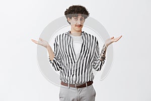 Waist-up shot of clueless good-looking and funny unaware guy with moustache and curly dark hair shrugging with spread