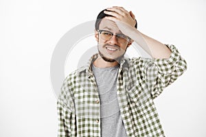 Waist-up shot of cocnerned and troubled upset guy with beard and moustache in black hipster beanie and glasses holding