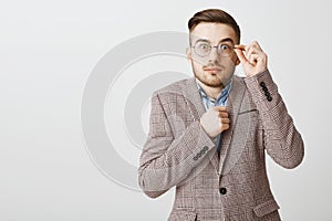Waist-up shot of cute shy and insecure male nerd in glasses and fancy jacket holding fist near body popping eyes photo