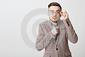 Waist-up shot of cute shy and insecure male nerd in glasses and fancy jacket holding fist near body popping eyes