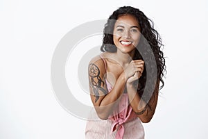 Waist-up shot elegant good-looking african american curly-haired female with tattoos, no blemishes, tilt head smiling